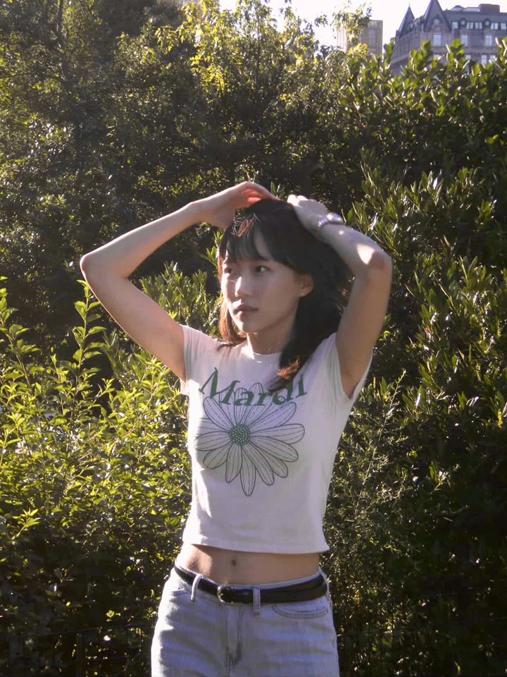 Summer outdoors with her hands on her head, in front of trees