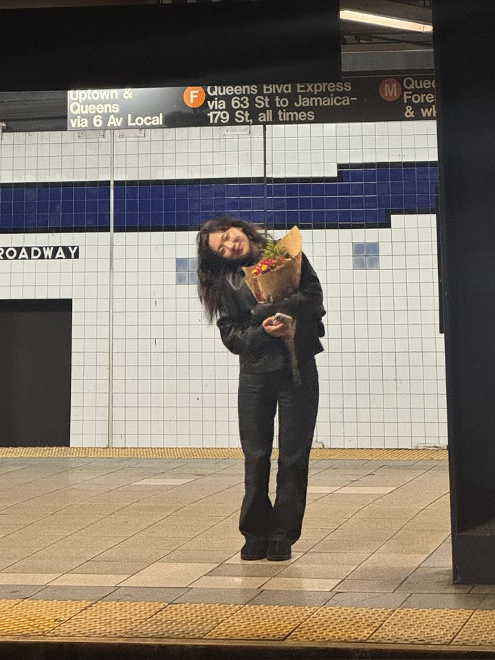 Summer holding a bouquet of flowers on a subway platform